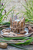 Windlicht umkleidet mit Pfahlmuschel in einem Kranz aus Clematis und Chinaschilf (Miscanthus)