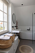 Modern bathroom with freestanding bathtub and round storage baskets