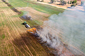 Aerial view of tractor pulling propane burner in hay field