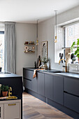 Modern kitchen with dark grey fronts, hanging pendant lights and wooden parquet flooring