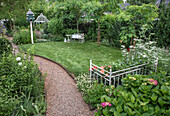 Grüner Garten mit gepflegtem Rasen und Sitzbank und Pavillon aus Metall