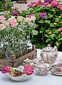 Vintage-Teeservice mit Rosen- und Hortensien-Sträußchen auf Gartentisch