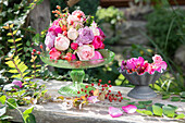 Flower arrangement with roses and rose hips on a rustic wooden table in the garden