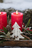 Rote Kerzen und Papier-Weihnachtsbaum, Beeren und Äste auf Baumrinde