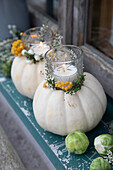 Pumpkin candle holder with flowers and tea lights on a rustic windowsill