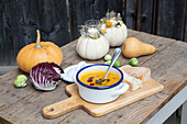 Wooden table decorated in autumn with pumpkin soup, bread and radicchio