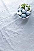 Bowl with blue coloured Easter eggs on linen fabric