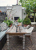 Wooden table, bench and chairs on terrace with plant decoration