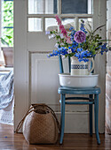 Meadow flowers in a jug, wash bowl and blue wooden chair in country house style