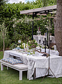 Festively laid garden table with white tablecloths and decorations made from natural materials