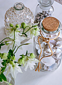 Glass bottles with shells and net on a white table