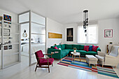 Living room with green corner sofa and colorful carpet