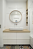 Modernes Badezimmer mit gemustertem Fliesenboden und rundem Spiegel