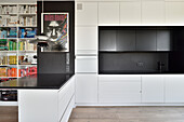Modern kitchen in white and bookshelf in a flat in Warsaw