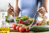 Frauenhände mixen einen gesunden Frühlingssalat aus verschiedenen Zutaten