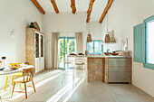 Bright kitchen with wood-beamed ceiling, natural stone counter and blue-painted window frames