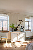 Vintage wooden chest of drawers, picture frame, bust and plant in bright living room