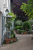 Gartenweg mit Pflanztöpfen und Sitzbereich vor einem Haus