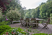 Wooden terrace with garden table and chairs with a view of the river and wooded banks