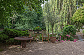 Gemütliche Sitzgruppe aus Korbmöbeln und Rundtisch im schattigen Garten