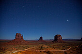 Sterne über den mondbeschienenen Mittens und Merrick Butte im Monument Valley Navajo Tribal Park in Arizona