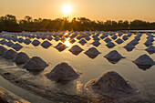 Piles of salt create geometric designs on the salt pan at a traditional evaporation salt farm in Samut Sakhon, Thailand.