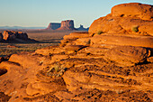 Farbenfroher erodierter Sandstein bei Sonnenuntergang im Mystery Valley im Monument Valley Navajo Tribal Park in Arizona. Die Monumente von Utah liegen dahinter.