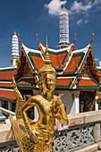 A golden Theppaksi statue guards the Wat Phra Kaew at the Grand Palace in Bangkok, Thailand. The Theppaksi is a half man, half bird guardian in Thai lore.