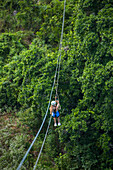 Eine junge Frau beim Ziplining über dem Regenwald in der Nähe von Sosua in der Dominikanischen Republik
