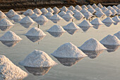 Salzhaufen bilden geometrische Muster auf der Salzpfanne in einer traditionellen Verdunstungssalzfarm in Samut Sakhon, Thailand