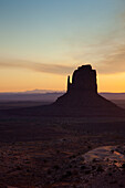 Colorful sunrise sky behind the East Mitten Butte in the Monument Valley Navajo Tribal Park in Arizona.