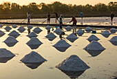 Workers producing salt by traditional methods used for thousands of years at a salt farm in Samut Sakhon,Thailand.