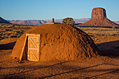 Das erste Licht auf einer traditionellen Navajo-Hütte im Monument Valley Navajo Tribal Park in Arizona. Mitchell Butte liegt dahinter