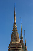 Die Turmspitzen des Phra Chedi Rai im buddhistischen Tempelkomplex Wat Pho in Bangkok, Thailand. Sie wurden von König Rama III. zur Aufbewahrung der Asche der königlichen Familie errichtet.