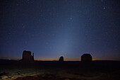 Zodiakallicht vor der Morgendämmerung über den Mittens und Merrick Butte im Monument Valley Navajo Tribal Park in Arizona. Das Zodiakallicht entsteht durch die Reflexion des Sonnenlichts an der interplanetaren Zodiakalstaubwolke und ist um die Frühlings- und Herbstsonnenwende sichtbar