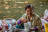 A Thai woman preparing food on her boat in the Damnoen Saduak Floating Market in Thailand.