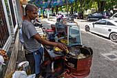 A Dominican man frying tostones in a mobile kitchen stand on the street in Santo Domingo, Dominican Republic.