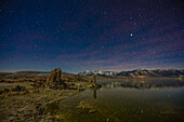 Sterne über mondbeschienenen Tuffsteinformationen im Mono Lake in Kalifornien mit den östlichen Sierra Mountains im Hintergrund