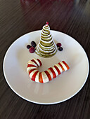 A Christmas holiday breakfast with a pancake Christmas tree and a banana & strawberry candy cane.