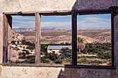 The window of an old ruin at Hot Springs frames the desert landscape and old post office in Big Bend National Park in Texas. The Sierra del Carmen Mountains in Mexico are in the distance.