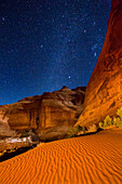 Orion und die Milchstraße über dem Sand beim Ear of the Wind Arch bei Nacht im Monument Valley Navajo Tribal Park in Arizona