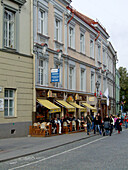People eating in a sidewalk cafe on the street in the historic Old Town of Vilnius, Lithuania. A UNESCO World Heritage Site.