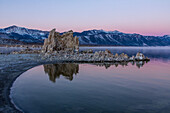 Nebel in der Morgendämmerung über den Tuffsteinformationen am Mono Lake in Kalifornien. Die östlichen Sierra-Berge sind im Hintergrund zu sehen.