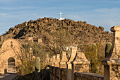 Gewölbter Durchgang durch die Schutzmauer um die Mission San Xavier del Bac, Tucson Arizona. Der Grottenhügel mit seinem weißen Kreuz liegt dahinter