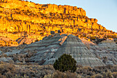 Sonnenuntergang an den Sandsteinklippen im nordwestlichen New Mexico, USA. Im Vordergrund ist ein erodierter Schieferhügel