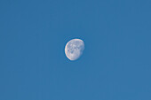 A waning gibbous moon photographed in the daytime with a telephoto lens over Utah.