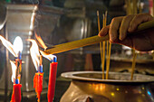 A worshipper lights joss sticks or incense in the Buddhist Man Mo Temple in Hong Kong, China.