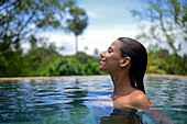 Young attractive woman enjoying a bath in the infinity edge swimming pool at The Dutch House, Galle, Sri Lanka
