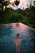 Young attractive woman enjoying a bath in the infinity edge swimming pool at The Dutch House, Galle, Sri Lanka