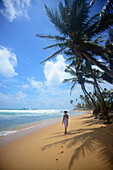 Young woman walking on Hikkaduwa beach at sunset, Sri Lanka